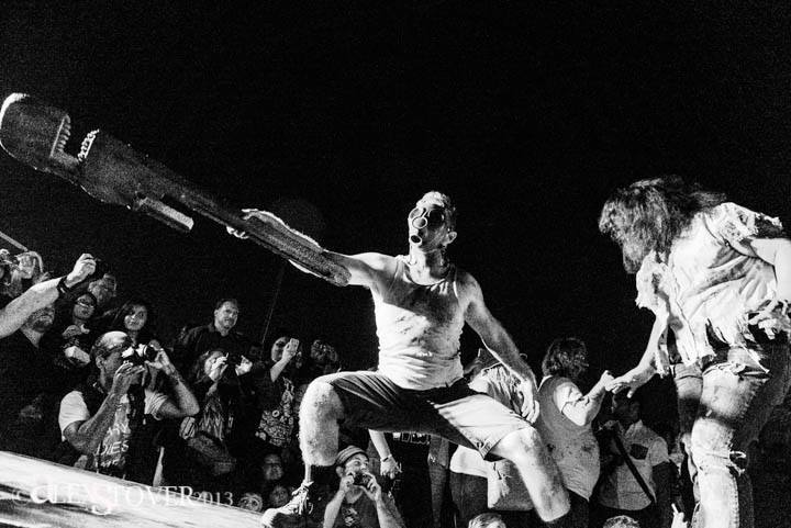 A cat walk for monsters. Muscular man wearing a gas mask holding a giant wrench out at fans.