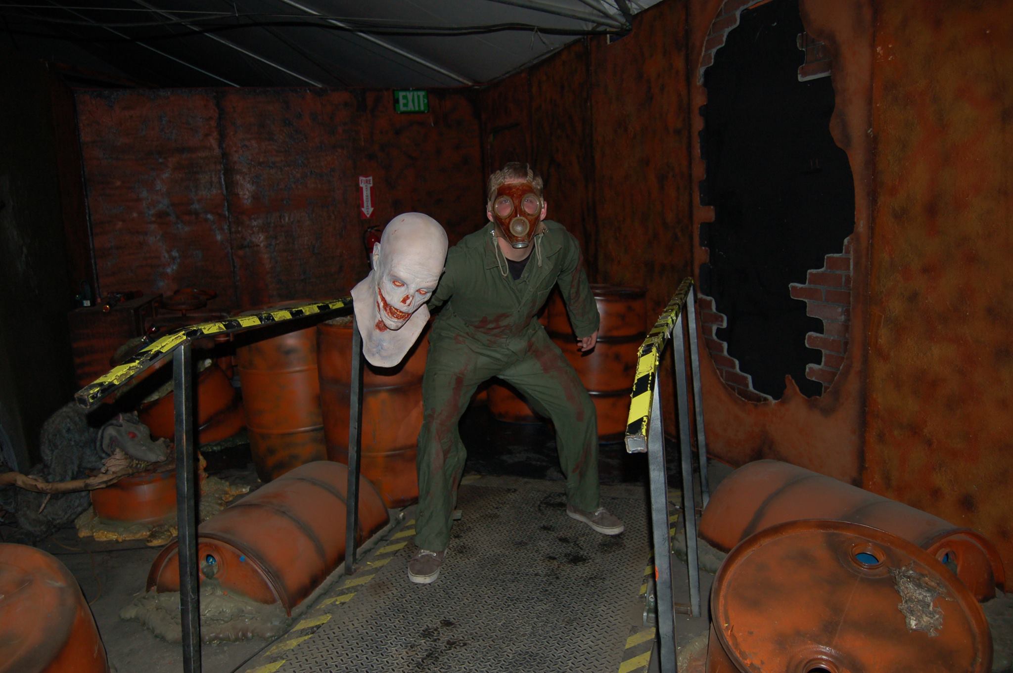 Gas mask scare actor in a toxic waste room with barrels